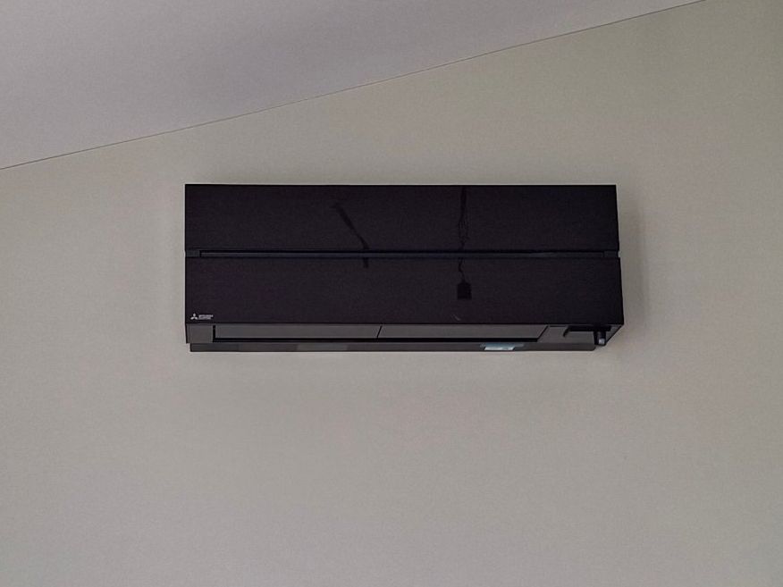 Witte airco-binnenunit en ventilatieventiel in een afgewerkte ruimte